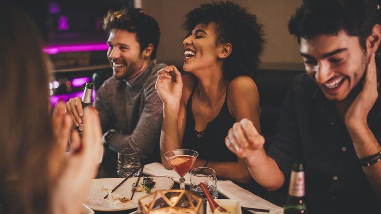 Friends at a table laughing over food and drinks