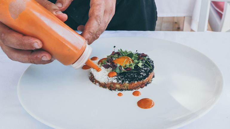 Line cook garnishing a dish