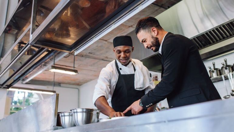 Manager and line cook together in a restaurant kitchen