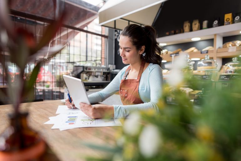 Woman working on some papers looking at her tablet