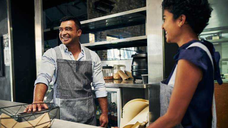 Employees behind restaurant counter smiling