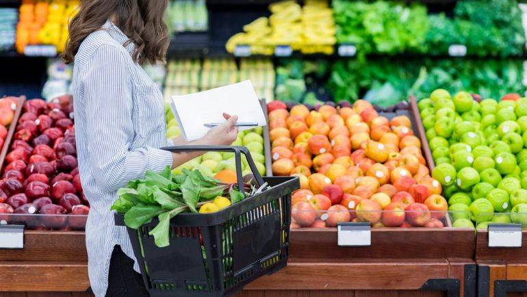 Shopper in produce aisle with greens in basket