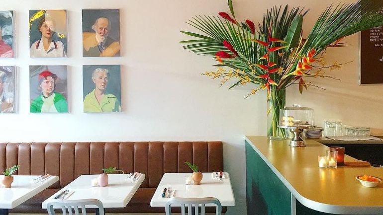 Restaurant with colourful flower arrangement and portraits on wall