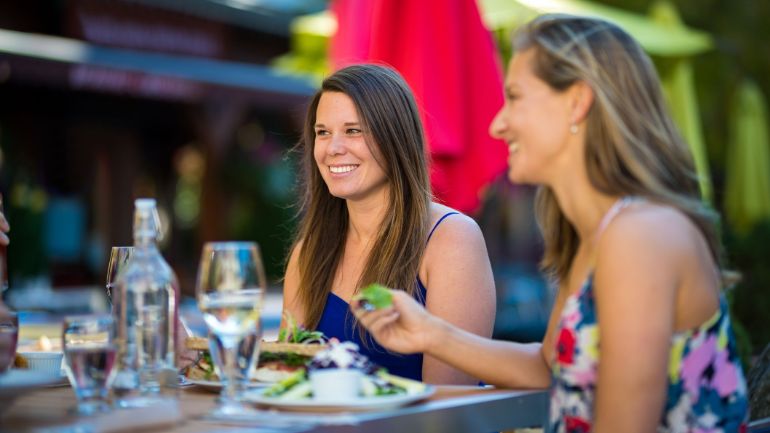 Two friends eating summer salads on a patio