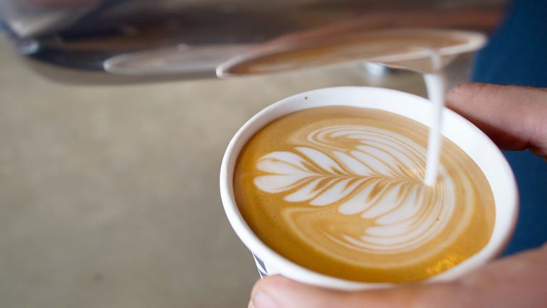 Barista creating a decorative image on the top of a cafe latte