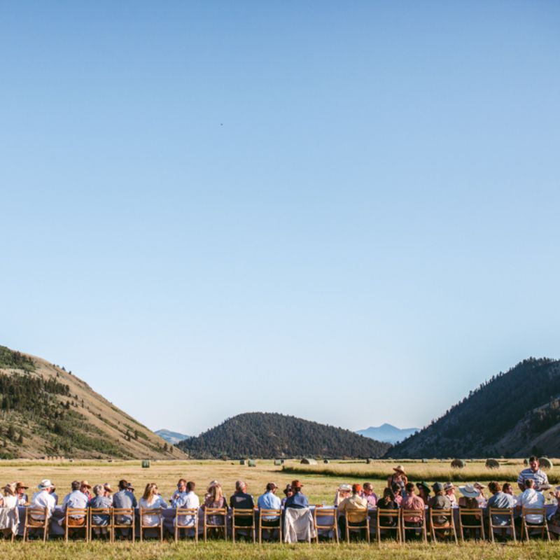 Diners seated at a long table with mountains in the background.