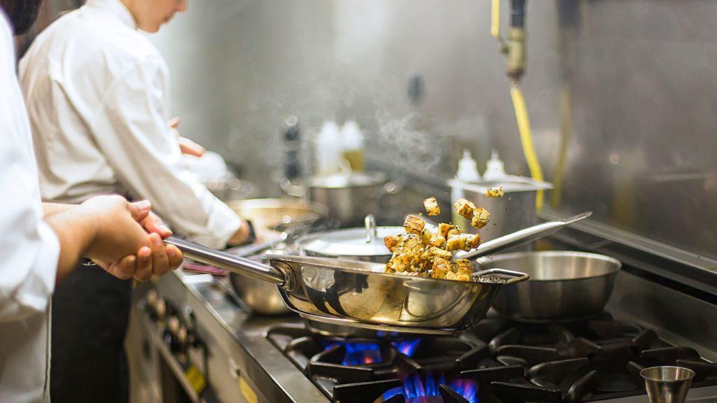 Chef sautéing over a commercial gas stove