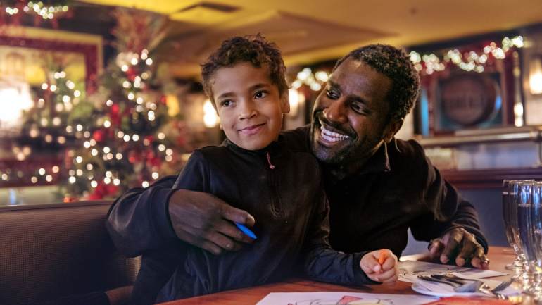 Father and son dining together in a dining room decorated for the holidays