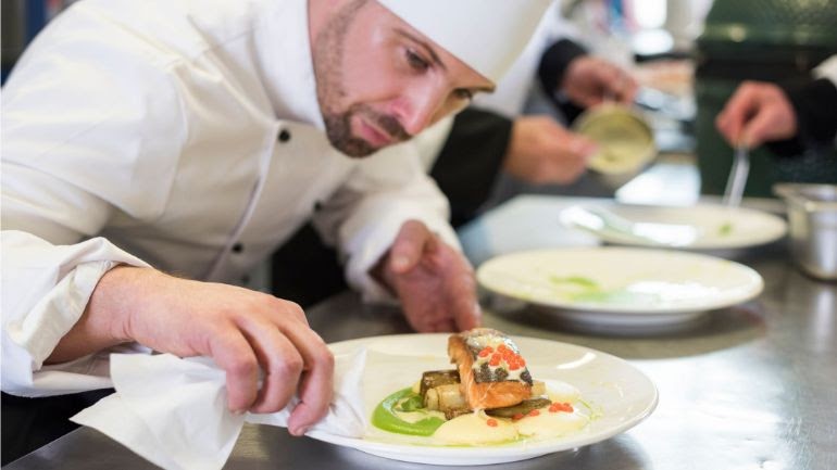 Chef cleaning the rim of a plate