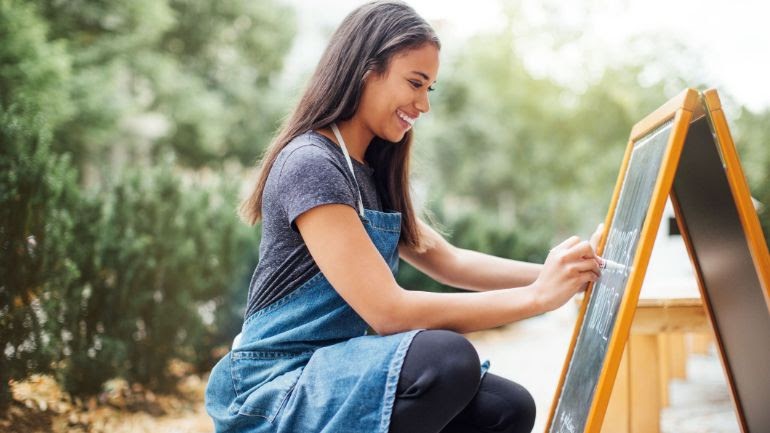 Restaurant employee writing the specials on a sandwich board