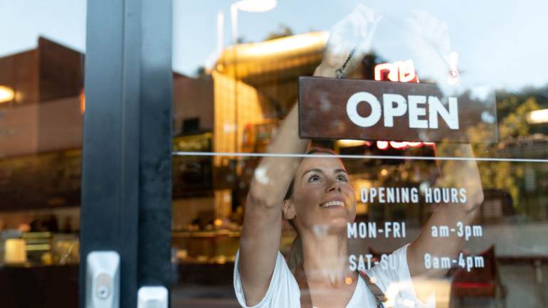 Employee hanging the open sign in the restaurant front window