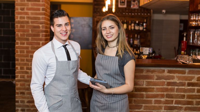 Two smiling servers standing in front of restaurant bar