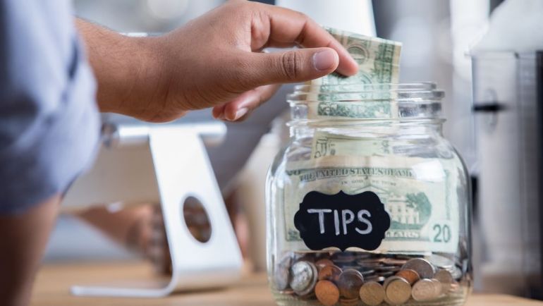 Customer putting a dollar bill into a tip jar
