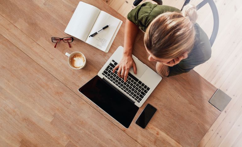 Restaurant owner working on laptop with notebook and coffee