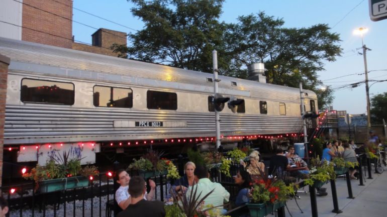 People dining outside an old L-train car