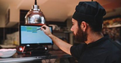 line cook checking orders on kitchen display screen