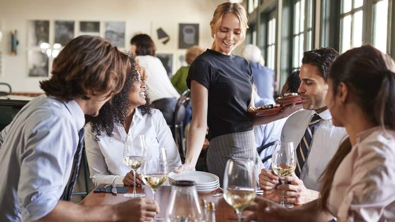 server dropping side plates to a table of diners