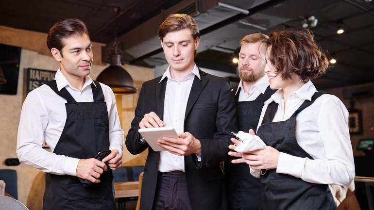 restaurant manager having staff meeting with POS on restaurant floor