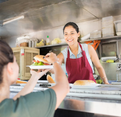 Food truck cook handing a dish with a burger to a customer