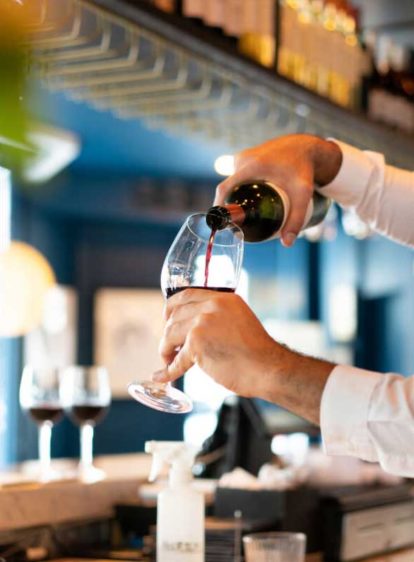 A server pouring wine into a glass