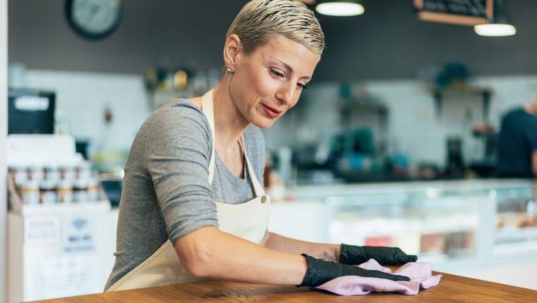 restaurant staff wearing gloves and sanitizing counter