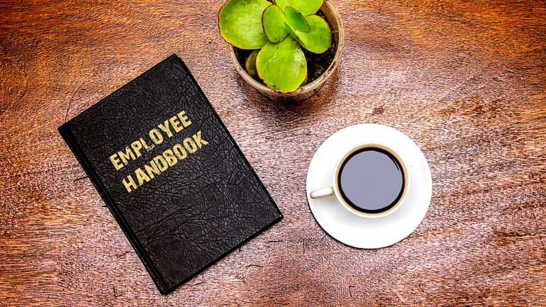 employee handbook lying beside a cup of coffee