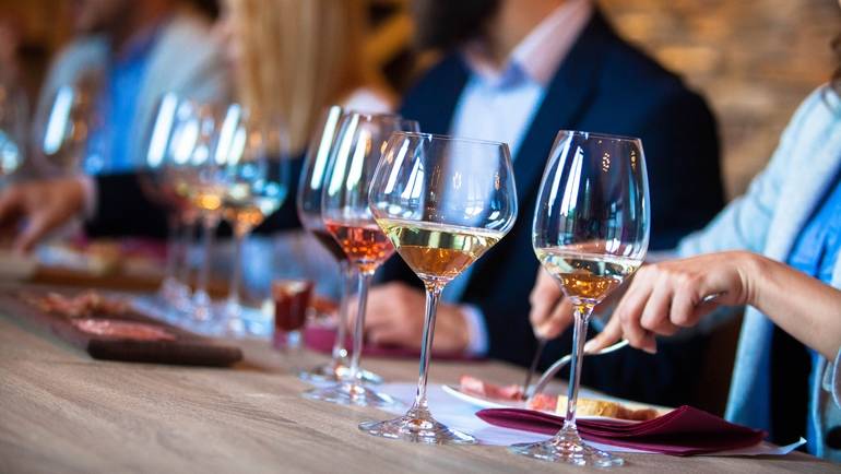 a row of diners tasting small bites with different wine offerings