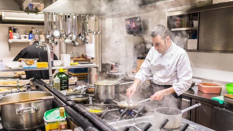 A chef cooking in a restaurant under a range hood