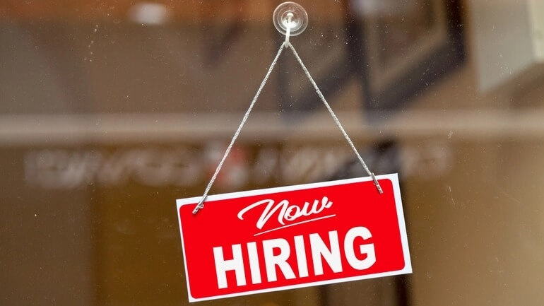 A "now hiring" sign on a restaurant window