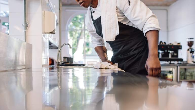 kitchen staff disinfecting stainless steel counter