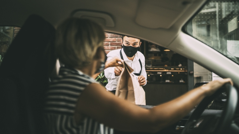 Young female driver arriving for curbside pickup at a restaurant