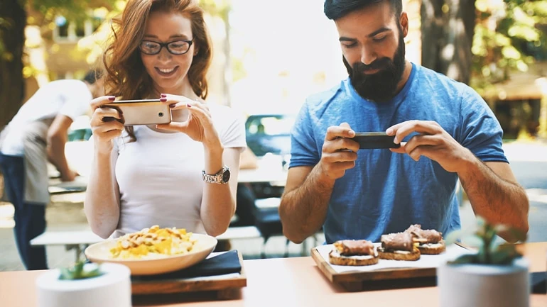 A couple taking picture of their restaurant meal for Instagram