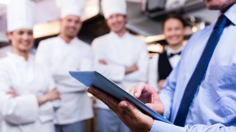 restaurant manager with POS speaking to front and back of house staff