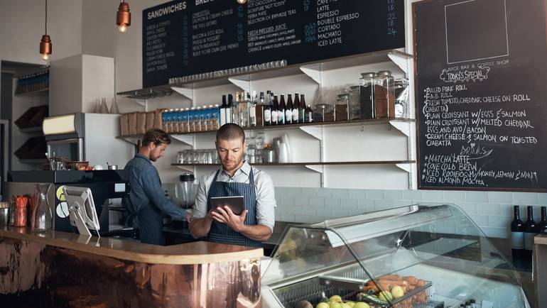 employee using POS behind cafe counter