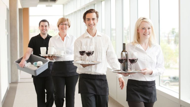 servers and busers carrying trays and pans