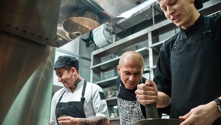 Chef overseeing the work of two back of house staff members