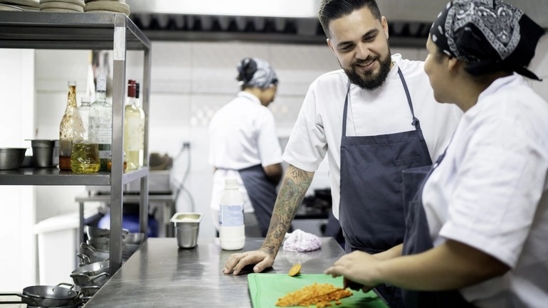 Chef talking a employee cutting carrots