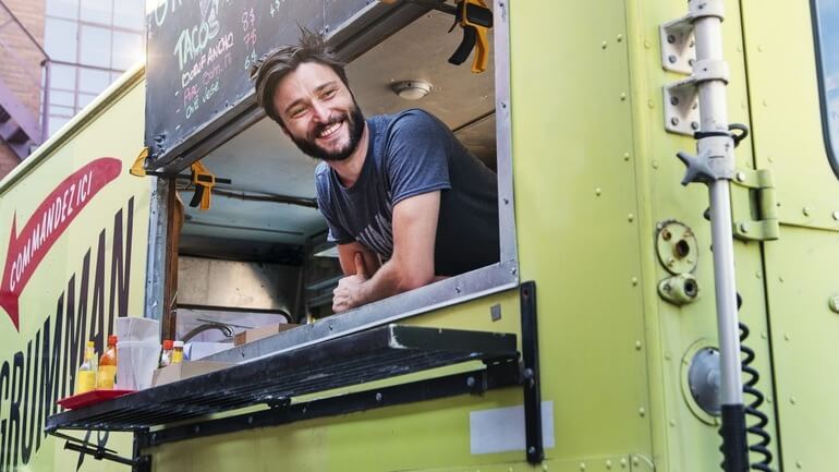 Food truck business owner leaning out the window of his food truck