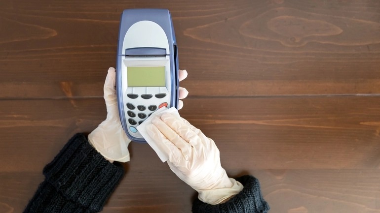 Woman cleaning a credit card reader with disposable wipes.