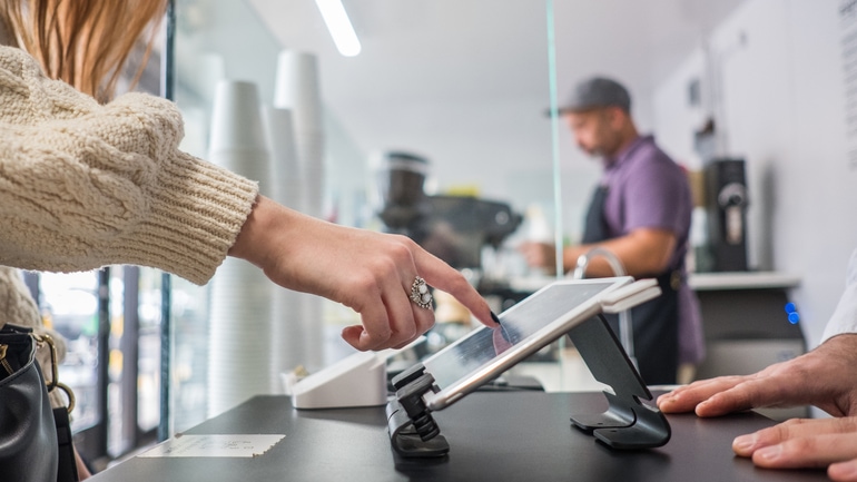 A female customer buying a coffee by using a touchscreen tablet.