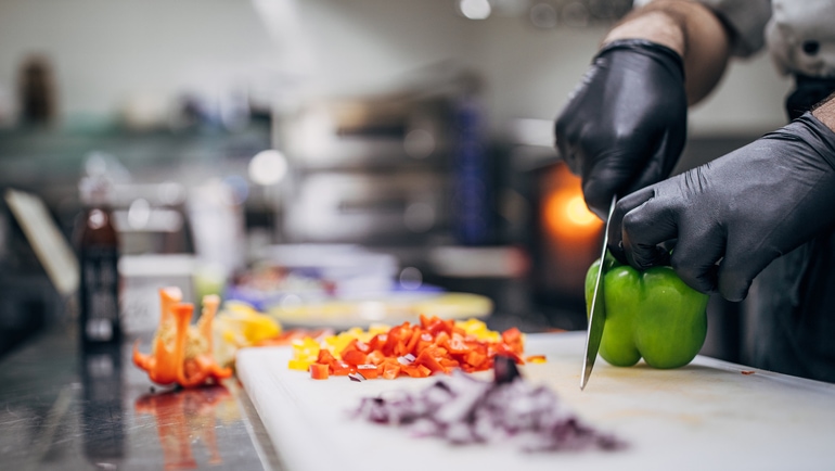 Chef cutting vegetables in a restaurant kitchen.