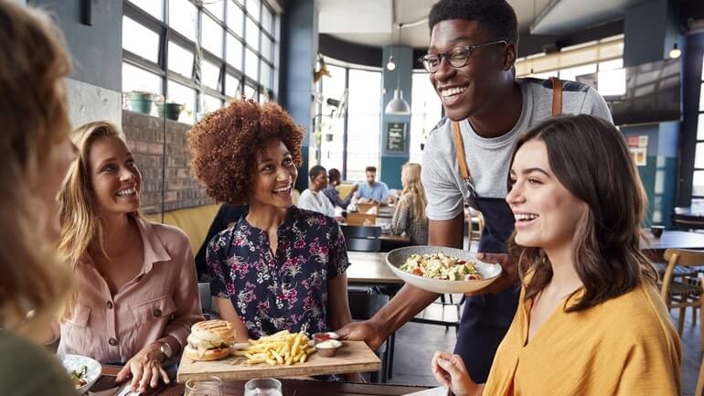 Waiter serving a group Of female friends meeting for drinks and food in a restaurant.