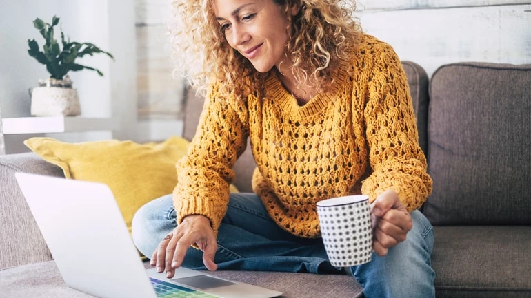 Woman sitting at home using a laptop and taking a restaurant survey.