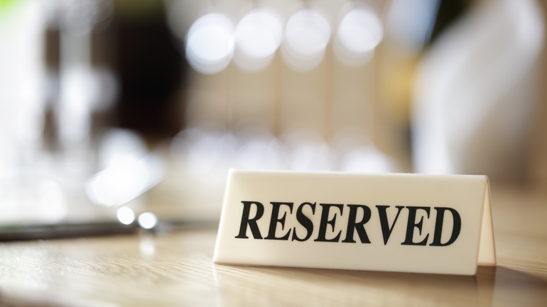 Reserved sign sitting on a table in a restaurant.