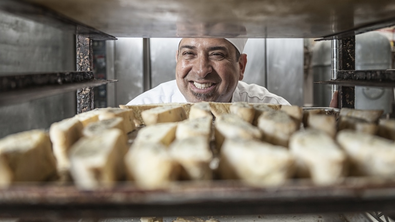 Backer looking at a tray of fresh bread.