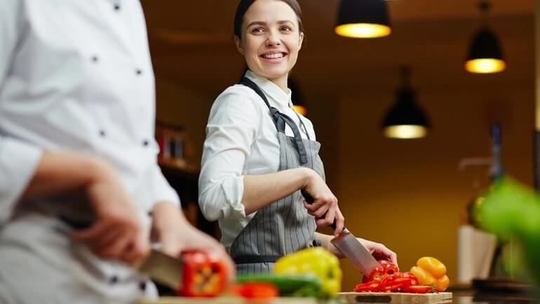 Chef cutting vegetables in a restaurant kitchen.