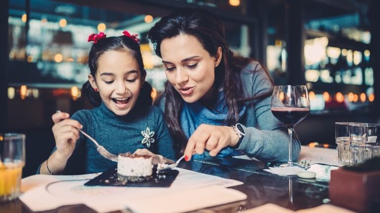 Mother and daughter sharing a dessert in a restaurant.