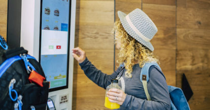 A woman using a self-ordering kiosk at a fast food restaurant.