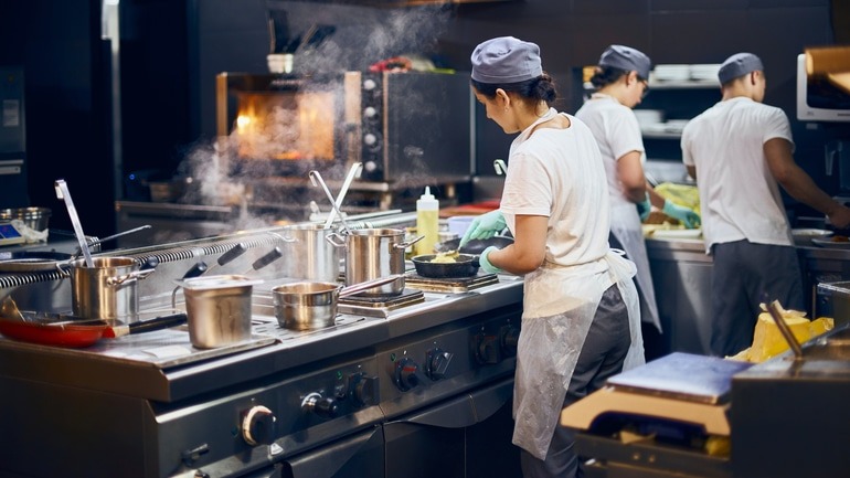 A team of cooks working in a commercial restaurant kitchen.