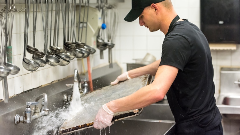 Dish washer working in a commercial restaurant kitchen.